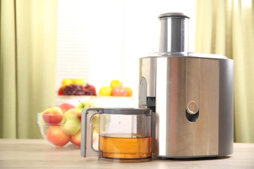 Juicer and apple juice on kitchen table
