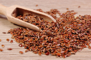 Heap of linseed with spoon on wooden background