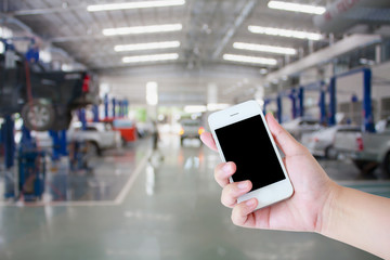 hand hold smartphone with car repair service center background