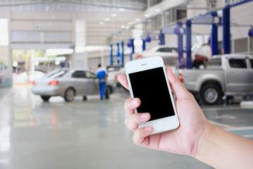 hand hold smartphone with car repair service center background