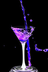 Cocktail glass with splashes on a black background.