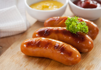 grilled sausage on wooden block serve with mustard and ketchup