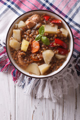 brown lentil soup with vegetables and meat close up. vertical top view 
