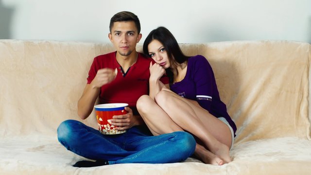 Young couple watching a scary movie: the girl is afraid