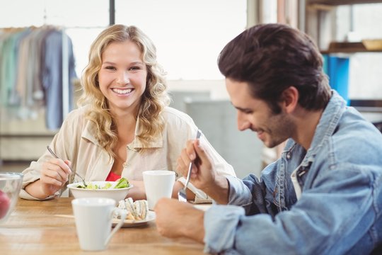 Smiling woman having breakfast with colleague in office