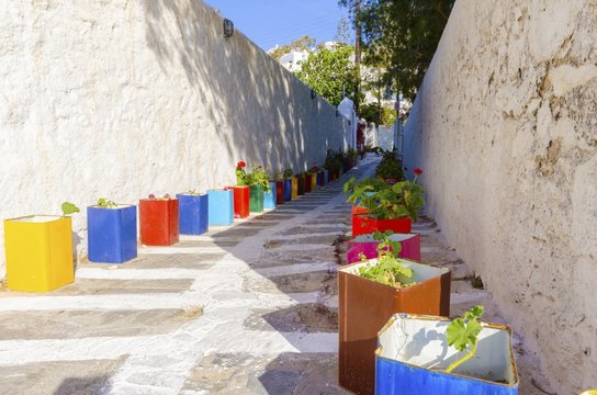 Mykonos alley, Greece. A typical greek island cobbled alley in Chora, Mykonos, Greece decorated with colourful flower pots of geranium and surrounded by whitewashed architecture.
