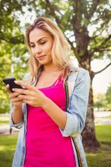 Happy woman using smartphone in park