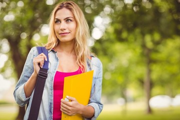 Smiling female student carrying bag and file 