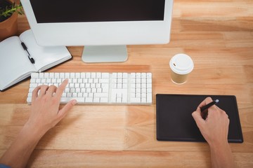 Man using graphics tablet while typing on keyboard