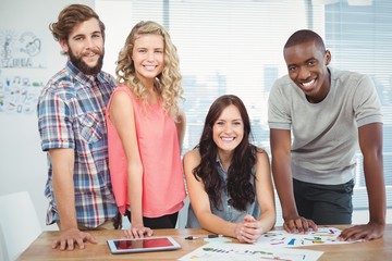 Portrait of happy woman with coworkers at desk 