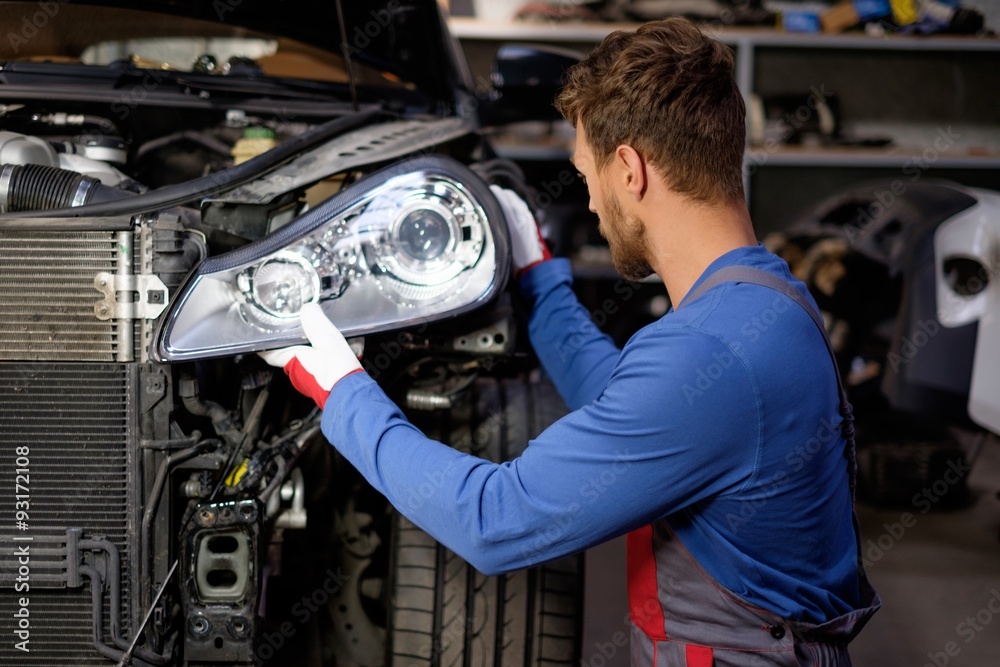 Poster Mechanic with new car headlight in a workshop