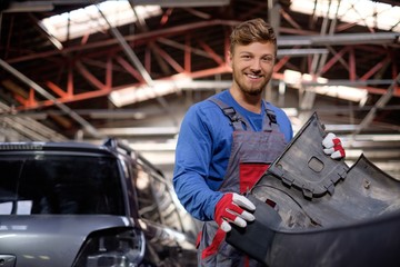 Mechanic with car bumper in a workshop