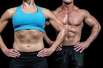 Fototapeta na wymiar Midsection of muscular woman and man standing with hands on hip