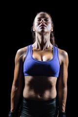 Naklejka premium Fit woman meditating against black background