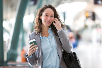 Young attractive business woman using smartphone drinking coffee