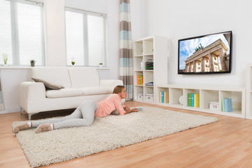Woman Lying On Carpet While Watching Television