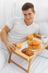 Obraz na płótnie Canvas Man eating breakfast in bed