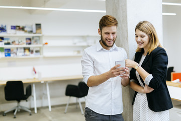 Couple smiling while looking the phone in office