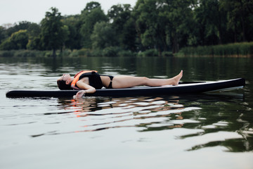 woman lying on a paddle board on water