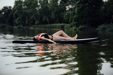 woman lying on a paddle board on water
