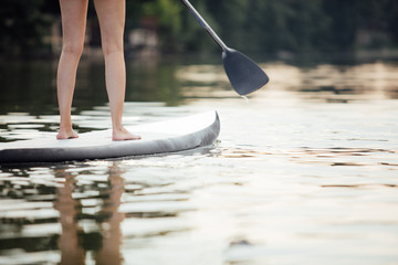 clouse-up of a woman legs on paddleboard - obrazy, fototapety, plakaty