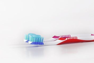 Two toothbrushes with blue toothpaste on white.