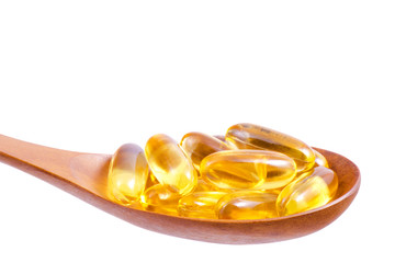Omega 3 fish oil capsules on wooden spoon isolated