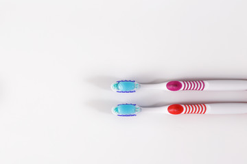 Obraz premium Two toothbrushes with blue toothpaste on white.