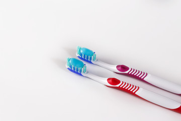 Two toothbrushes with blue toothpaste on white.