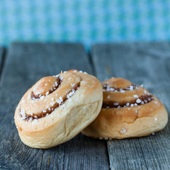 två kanelbullar på mörk träbakgrund