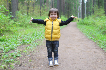 Cute child walks in the pine wood
