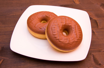 Sweet donuts with chocolate on wooden table