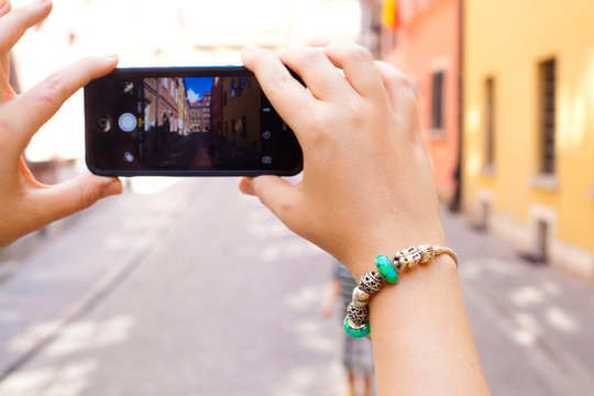 Tourist taking pictures on her phone. Hands with beautiful bracelet holding phone