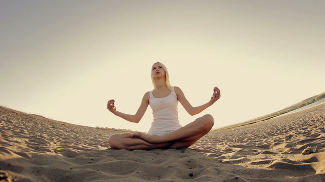 Young beautiful girl in white clothes doing yoga at sunset