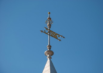 Fototapeta na wymiar Vintage gilded weathervane - flag on the tower against the blue sky