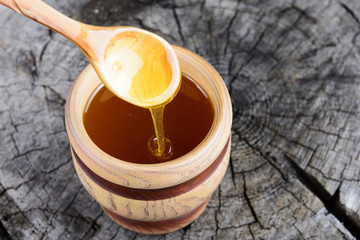 jar of honey and spoon with honey on a wooden background