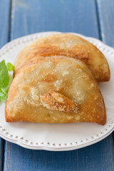 pie with meat with basil on white plate on blue wooden background