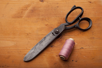 dressmaker shears craft concept with spool on wooden texture