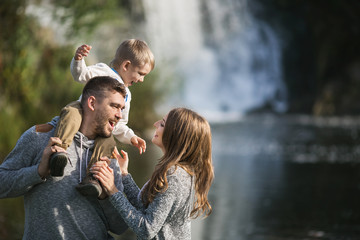 Portrait of a young parents with their son near a waterfall