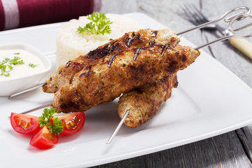 Barbecued kofta - kebeb with rice and vegetables on a plate.