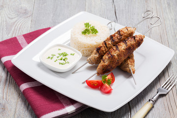Barbecued kofta - kebeb with rice and vegetables on a plate.