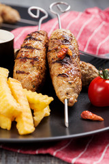 Barbecued kofta - kebeb with fries and vegetables on a plate.