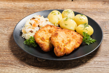 Fried pork chop in breadcrumbs, served with boiled potatoes and