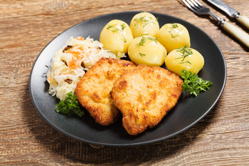 Fried pork chop in breadcrumbs, served with boiled potatoes and