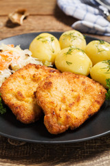 Fried pork chop in breadcrumbs, served with boiled potatoes and