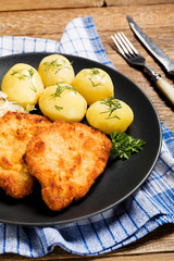 Fried pork chop in breadcrumbs, served with boiled potatoes and