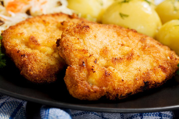 Fried pork chop in breadcrumbs, served with boiled potatoes and