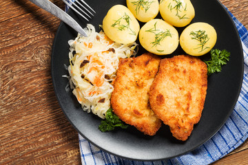 Fried pork chop in breadcrumbs, served with boiled potatoes and