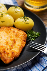 Fried pork chop in breadcrumbs, served with boiled potatoes and