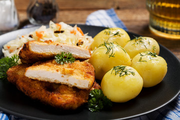 Fried pork chop in breadcrumbs, served with boiled potatoes and
